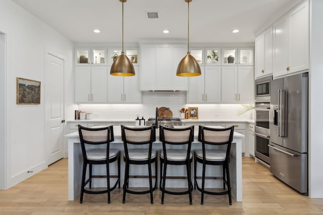 kitchen with white cabinets, light wood-style floors, appliances with stainless steel finishes, and light countertops