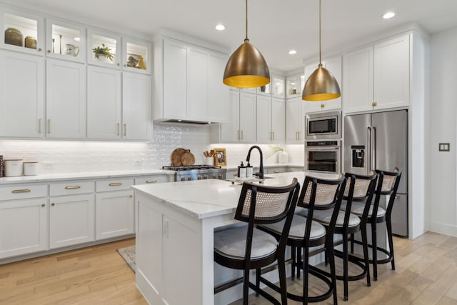 kitchen featuring white cabinets, light wood finished floors, stainless steel appliances, and a sink