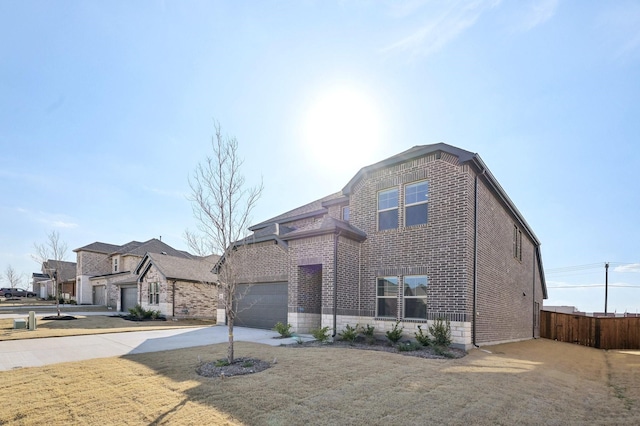 view of front of house with driveway, brick siding, an attached garage, and fence