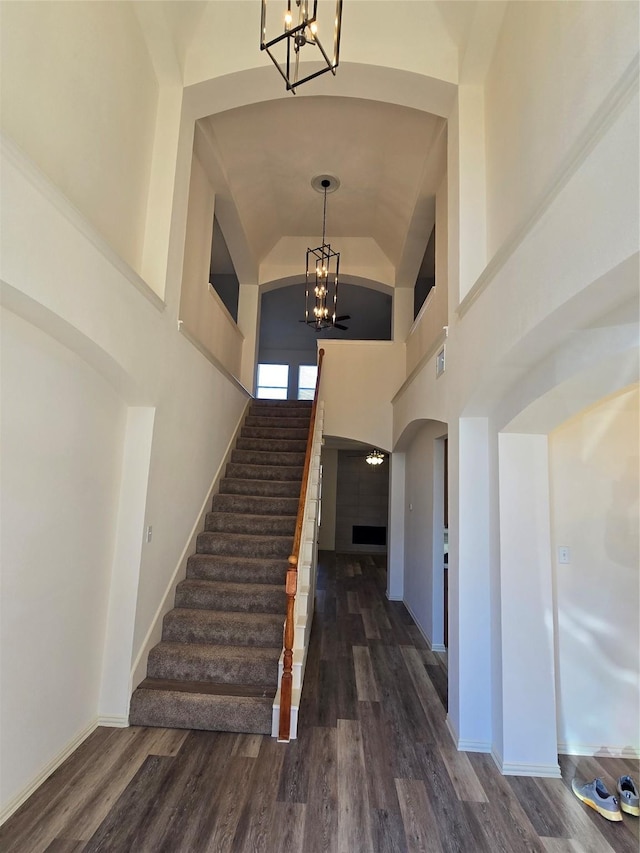 foyer entrance featuring a notable chandelier, a high ceiling, wood finished floors, baseboards, and stairway