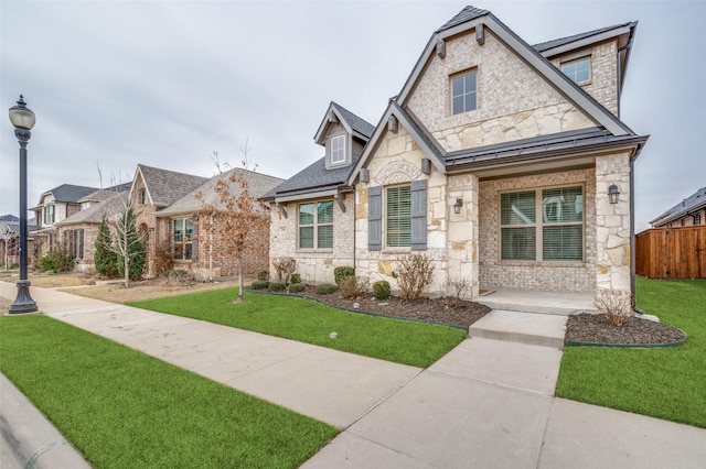 view of front facade with stone siding, fence, and a front yard