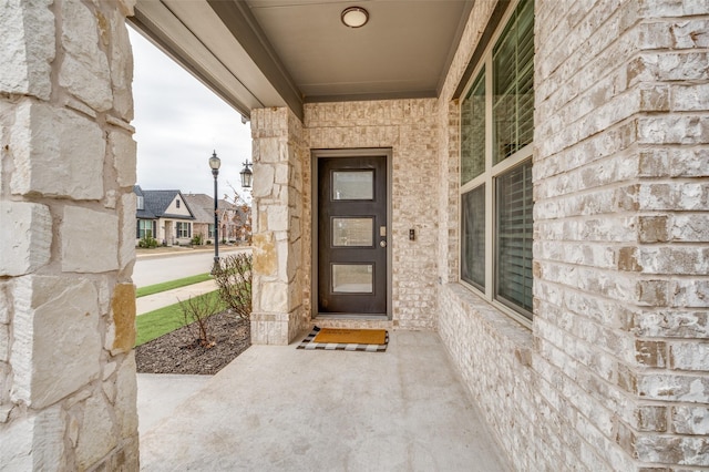 property entrance featuring covered porch and stone siding