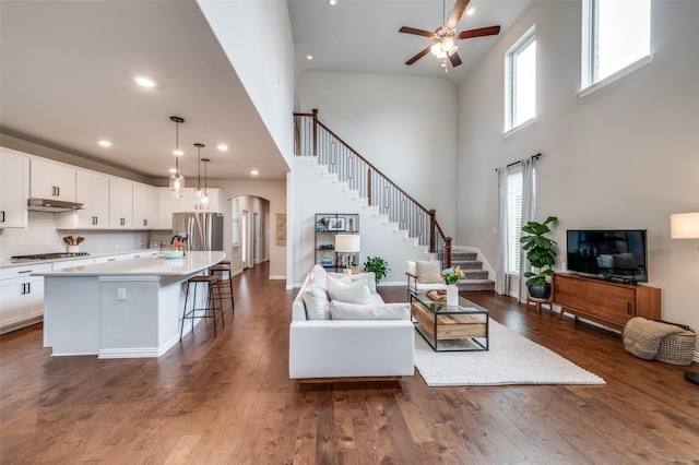 2064 Olivereta Dr, Little Elm, TX 75068 - living room featuring a high ceiling, a ceiling fan, stairway, arched walkways, and dark wood-style floors