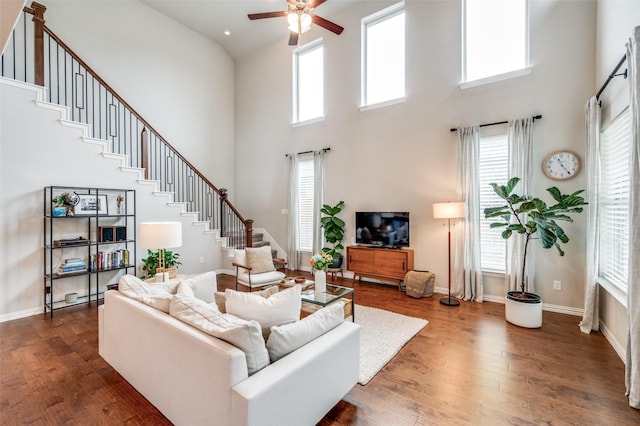 living room with a ceiling fan, wood-type flooring, stairway, and baseboards