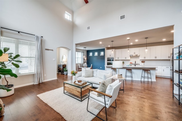 2064 Olivereta Dr, Little Elm, TX 75068 - living area with arched walkways, hardwood / wood-style floors, a towering ceiling, baseboards, and recessed lighting