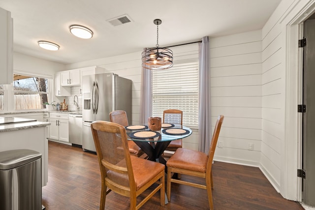 dining space with wood walls, dark wood finished floors, and visible vents