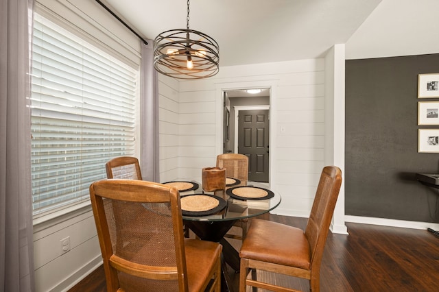 dining space with wood walls, baseboards, and dark wood finished floors