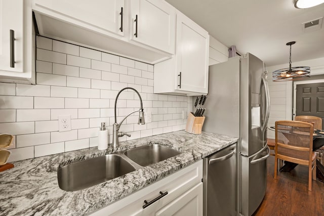 kitchen with visible vents, decorative backsplash, appliances with stainless steel finishes, white cabinetry, and a sink