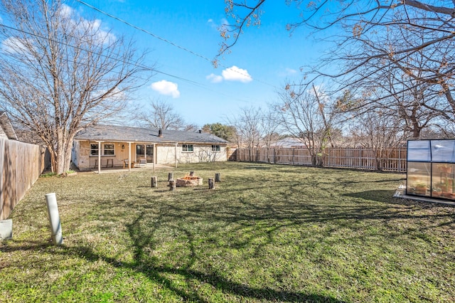 view of yard featuring a fenced backyard, a fire pit, an exterior structure, and an outdoor structure