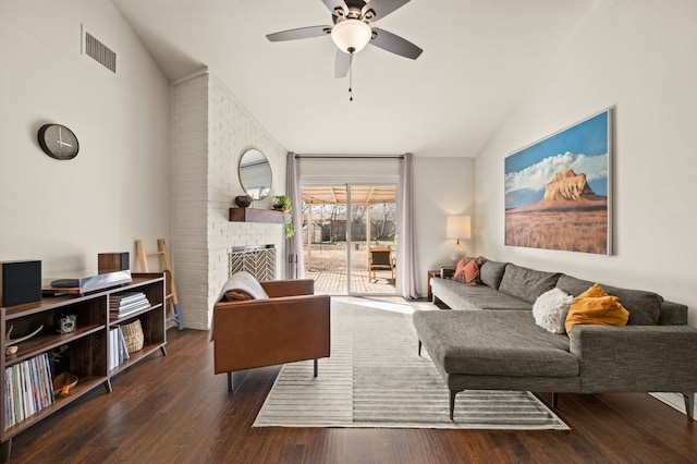 living area featuring lofted ceiling, a brick fireplace, visible vents, and wood finished floors