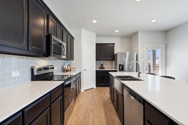 kitchen with decorative backsplash, light wood-style flooring, appliances with stainless steel finishes, light countertops, and recessed lighting