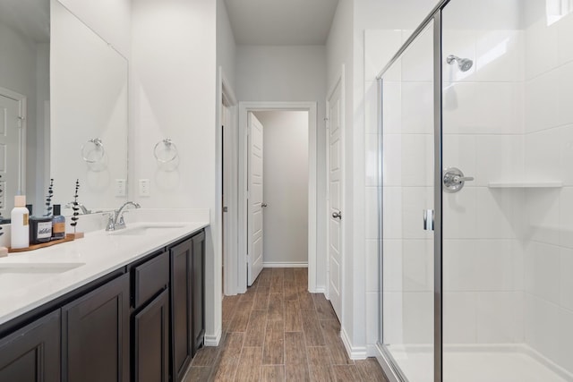 bathroom featuring a stall shower, double vanity, a sink, and wood tiled floor