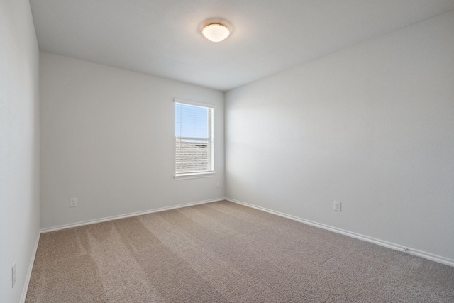 carpeted spare room featuring baseboards