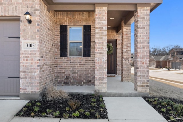 doorway to property featuring brick siding and an attached garage