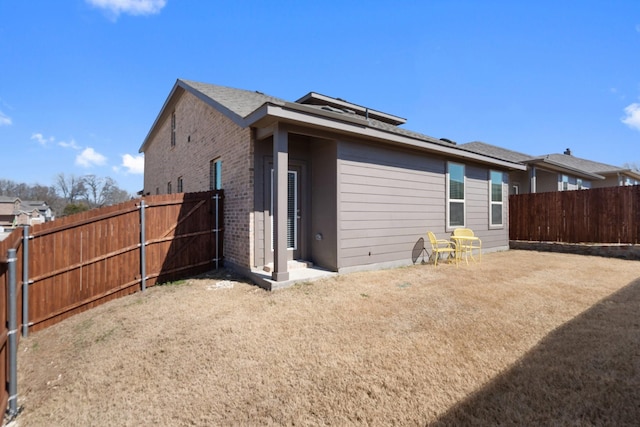 view of side of home featuring brick siding and a fenced backyard