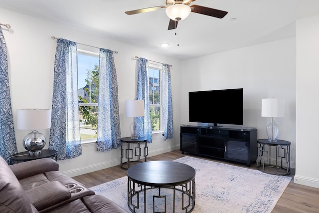 living room featuring a ceiling fan, baseboards, and wood finished floors