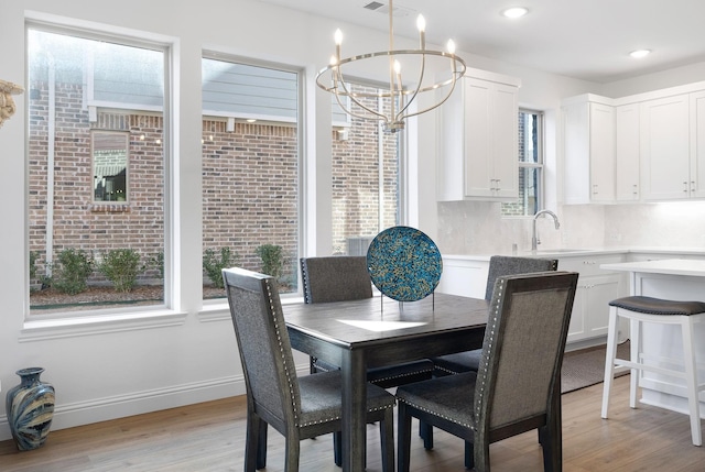 dining room featuring light wood-style flooring, baseboards, a notable chandelier, and recessed lighting