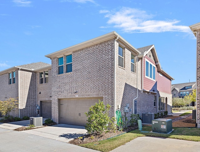 view of home's exterior featuring concrete driveway, brick siding, an attached garage, and central AC unit