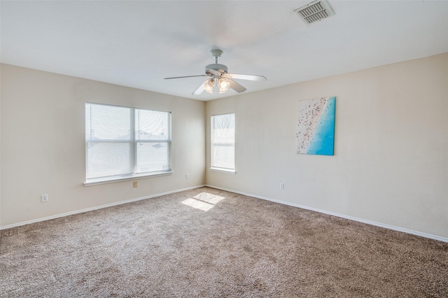 carpeted spare room featuring a ceiling fan, visible vents, and baseboards