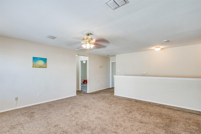 carpeted empty room featuring baseboards, visible vents, and a ceiling fan