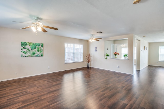 spare room featuring dark wood-style flooring, visible vents, and baseboards