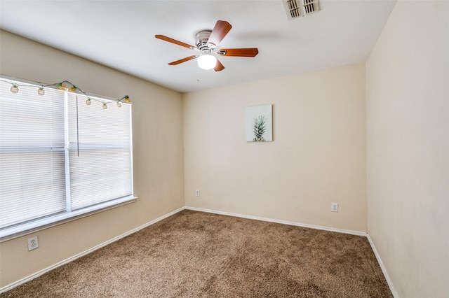 carpeted spare room featuring ceiling fan, visible vents, and baseboards