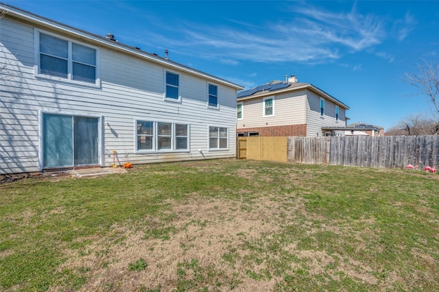 rear view of property featuring a lawn and fence