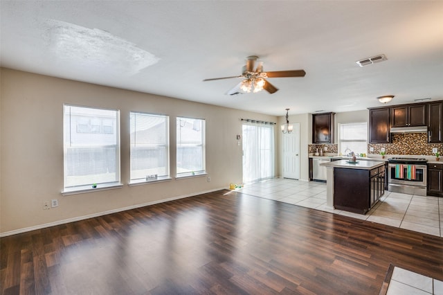 kitchen featuring dark brown cabinetry, under cabinet range hood, visible vents, appliances with stainless steel finishes, and a center island