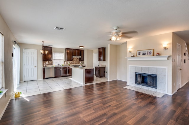 unfurnished living room featuring visible vents, a ceiling fan, baseboards, light wood finished floors, and a tiled fireplace