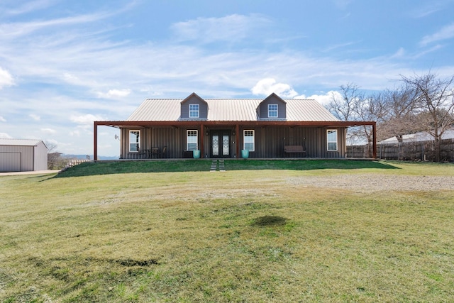 country-style home with metal roof, board and batten siding, a front yard, and an outdoor structure