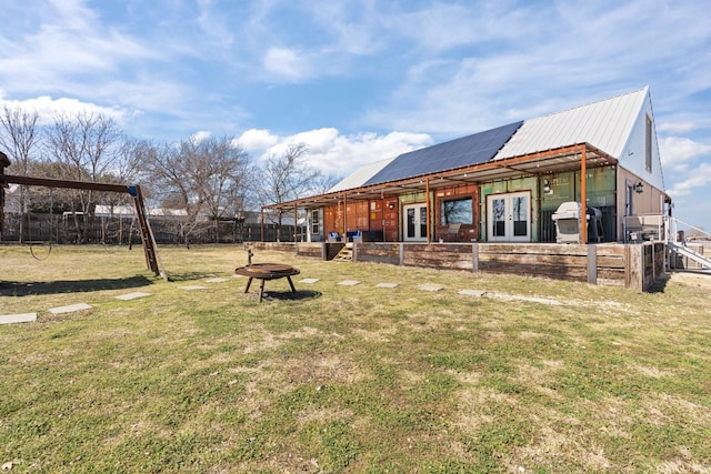 exterior space with metal roof, an outdoor fire pit, fence private yard, french doors, and a lawn