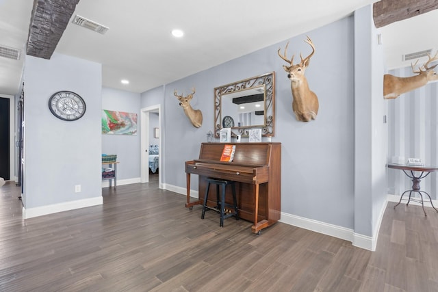 hall featuring wood finished floors, visible vents, and baseboards