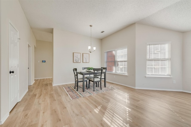 dining room featuring visible vents, baseboards, a textured ceiling, light wood-style floors, and a chandelier