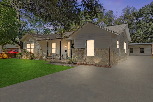 ranch-style house featuring a yard and stone siding