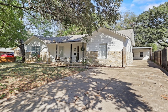 view of front facade featuring a garage, stone siding, fence, and a porch