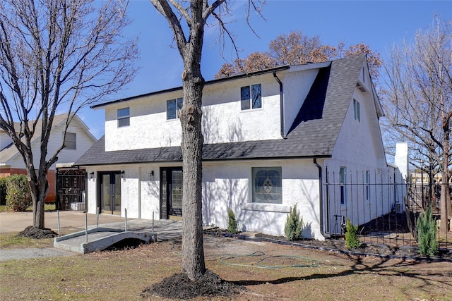 view of front facade featuring roof with shingles, a patio area, and stucco siding