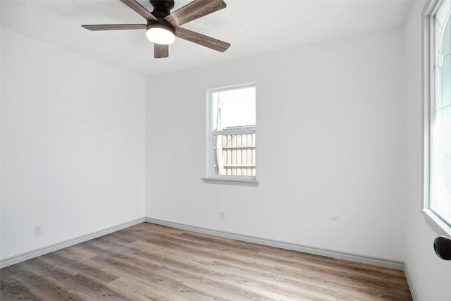 spare room featuring a textured ceiling, wood finished floors, a ceiling fan, and baseboards