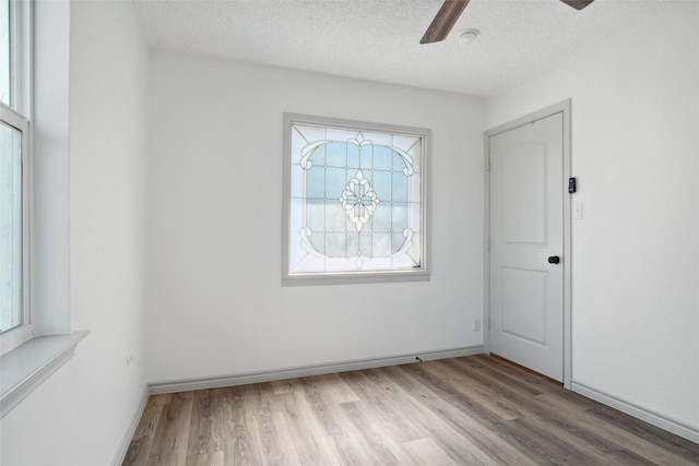 unfurnished room featuring ceiling fan, a textured ceiling, baseboards, and wood finished floors