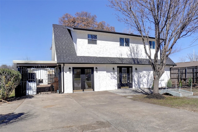 view of front of home featuring french doors, roof with shingles, fence, and stucco siding