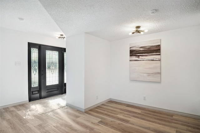 entryway featuring a textured ceiling, baseboards, and wood finished floors