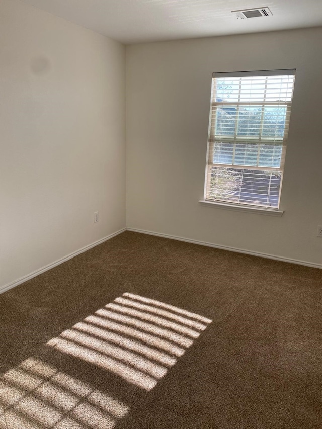 carpeted empty room featuring baseboards and visible vents