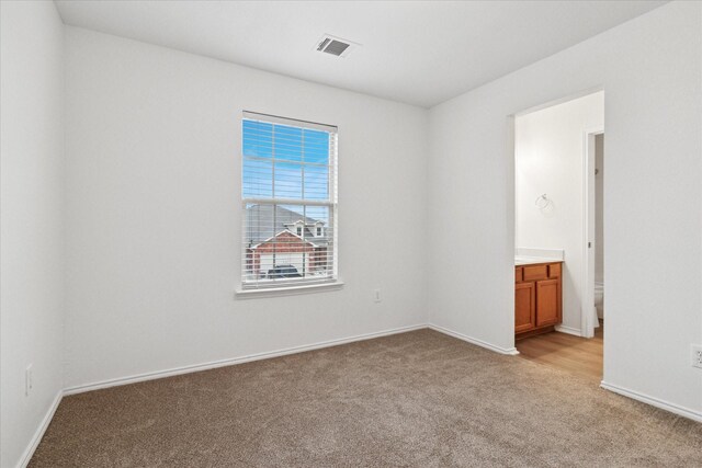 empty room featuring visible vents, light carpet, and baseboards