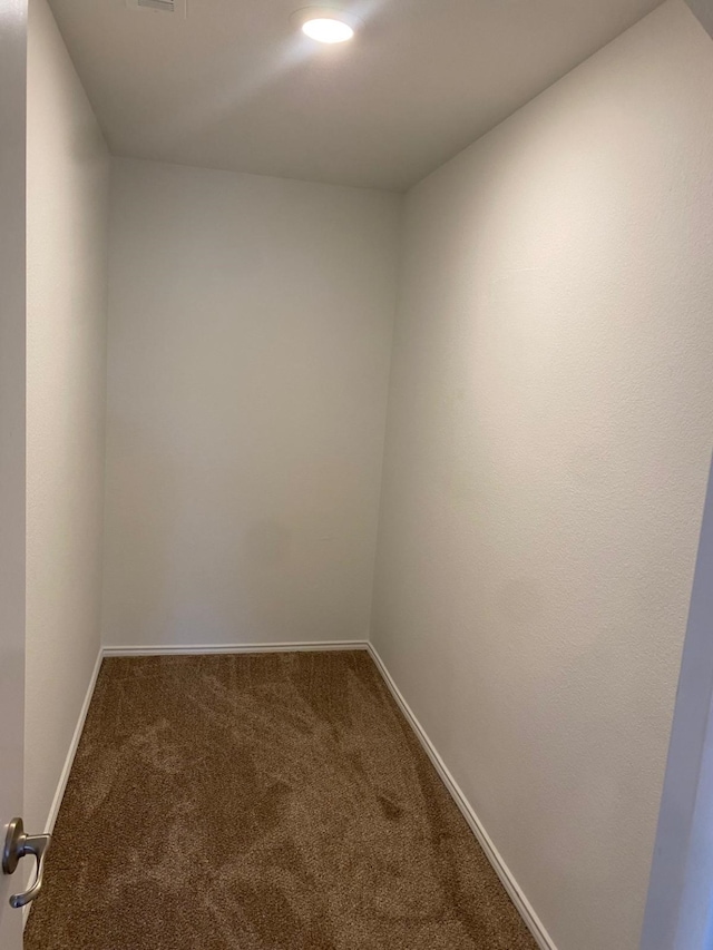 spare room with dark colored carpet and baseboards