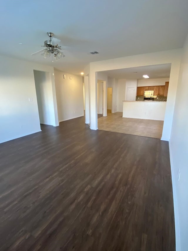 unfurnished living room featuring dark wood-style flooring and ceiling fan