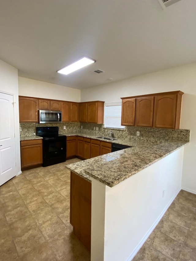 kitchen featuring a peninsula, a sink, light stone countertops, black appliances, and brown cabinetry