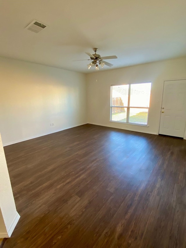 unfurnished room featuring baseboards, dark wood-style flooring, visible vents, and a ceiling fan