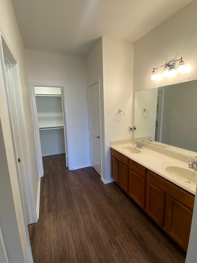 bathroom featuring double vanity, a sink, baseboards, and wood finished floors