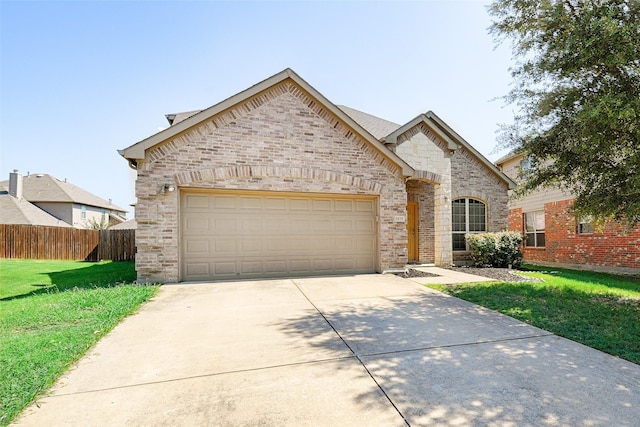 french country inspired facade with a garage, concrete driveway, fence, a front lawn, and brick siding