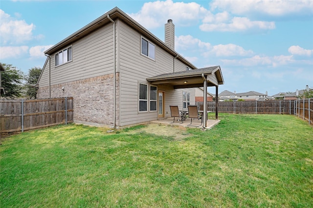 back of house with brick siding, a chimney, a lawn, a patio area, and a fenced backyard