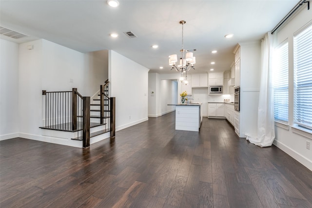 kitchen with dark wood finished floors, stainless steel appliances, recessed lighting, visible vents, and a kitchen island